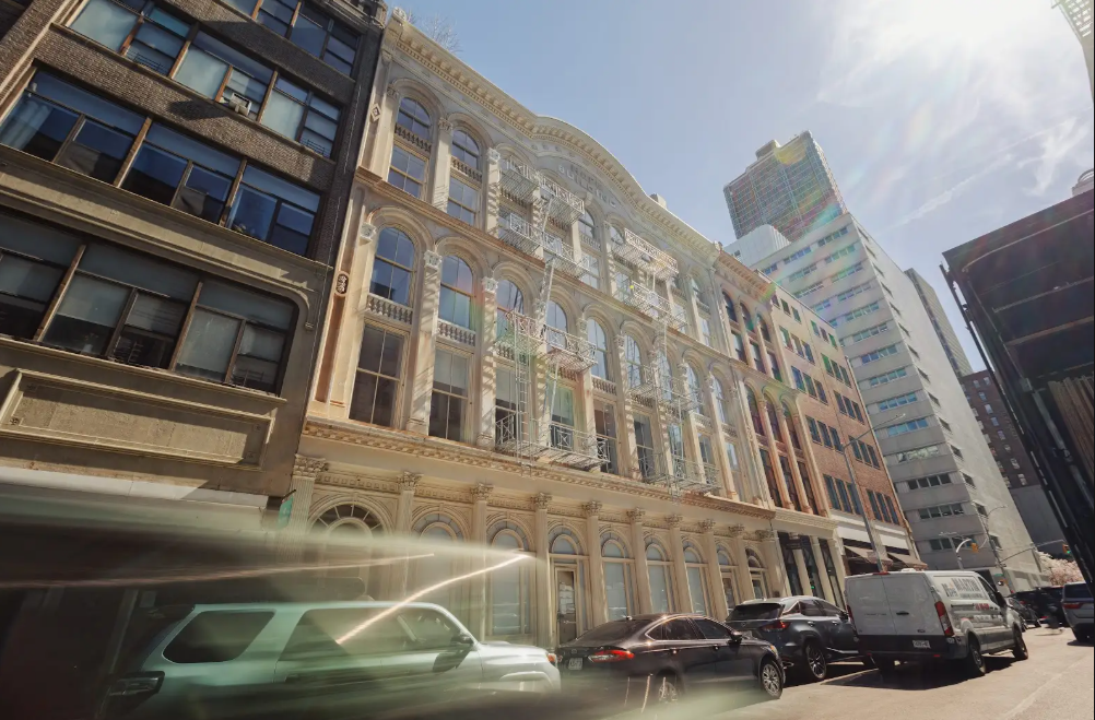Dynamic low-angle view of a decorative building facade with blurred street traffic and sunlight flares.