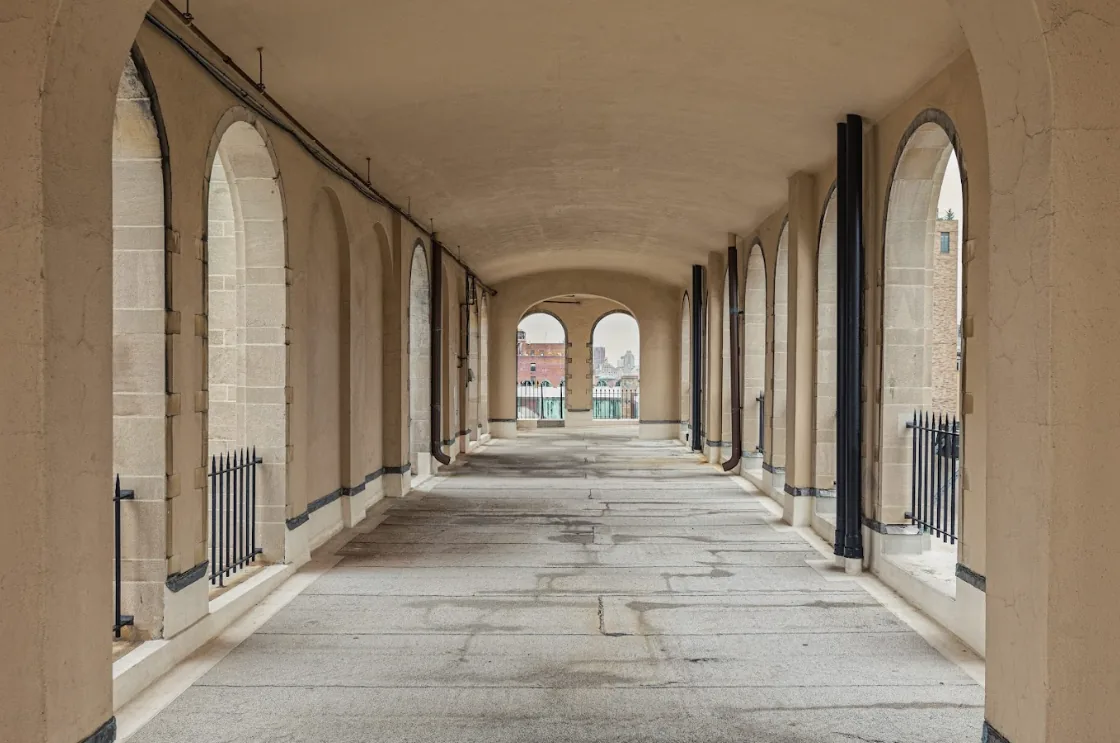 Long, arched hallway leading to an outdoor view, demonstrating architectural perspective.