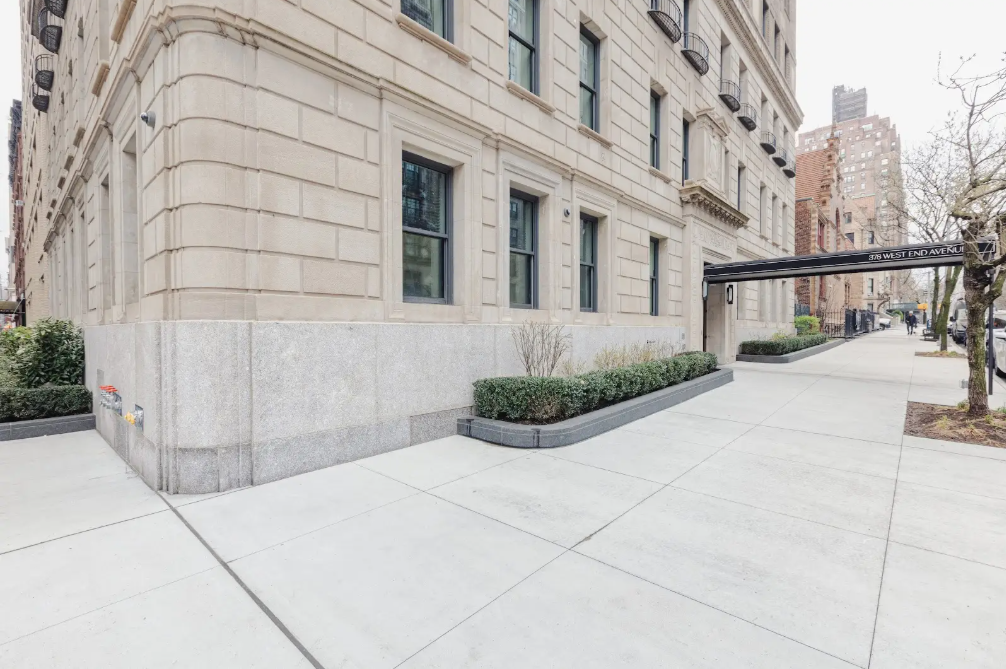 Elegant residential building exterior with a clean sidewalk and landscaping, viewed from a corner.